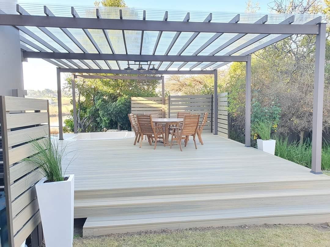 Completed modern pergola over a landscaped grey composite deck and outdoor dining area