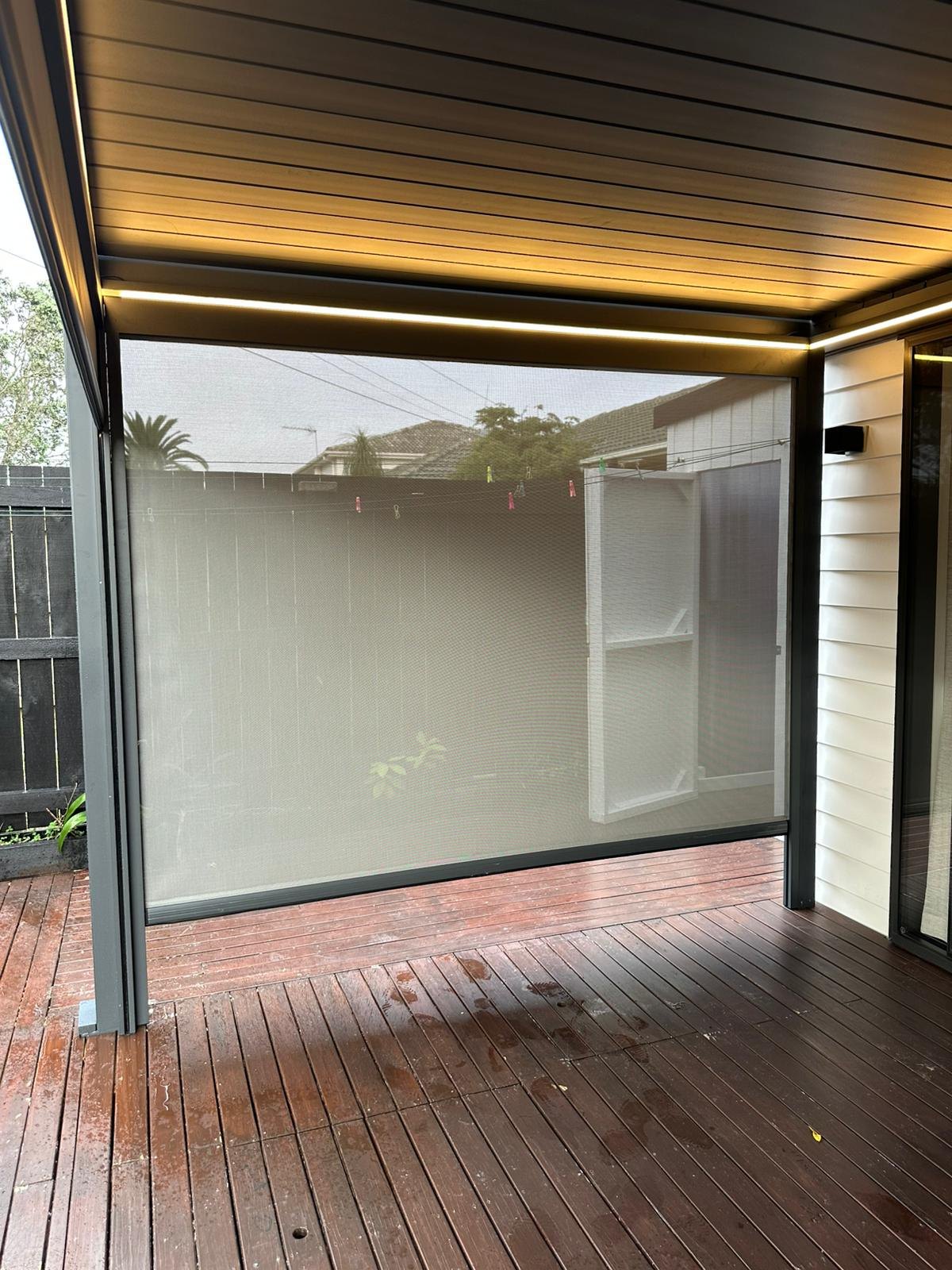 Finished pergola with a full-height weather screen and warm integrated lighting